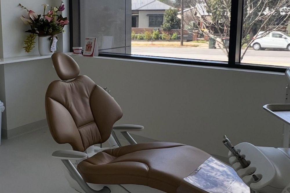 Modern brown leather dental treatment chair and clinical equipment in a brightly lit room-